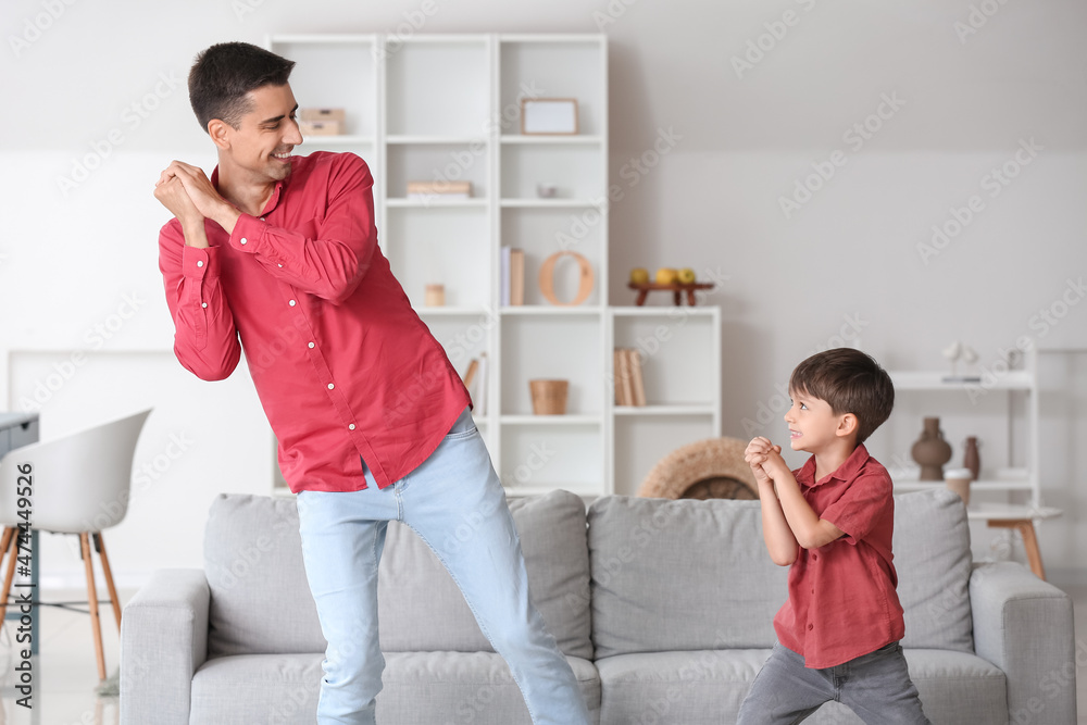 Man and his little son dancing at home