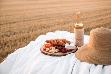 Wall Mural - Picnic with tasty snack and wine on haystack in harvested field