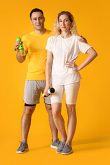 Poster - Sporty couple with bottles of water on color background