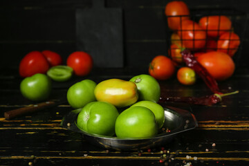 Bowl of fresh green tomatoes on dark wooden table