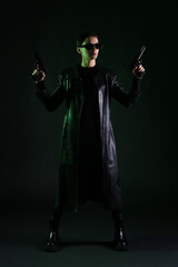 Wall Mural - Woman with guns dressed in matrix style on dark background