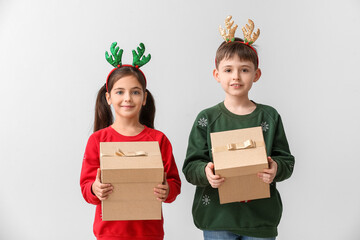 Wall Mural - Funny little children with reindeer horns and Christmas gifts on light background