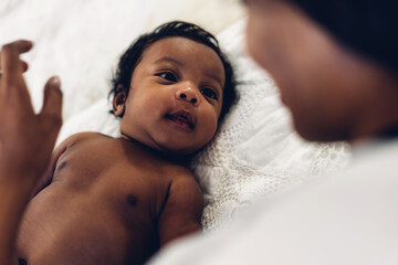 Wall Mural - Portrait of enjoy happy love family african american mother playing and kiss with adorable little african american baby.Mom touching with cute son in a white bedroom