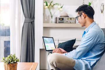 Wall Mural - Young smiling asian man using laptop computer working and study with document at home.Young creative man with new startup project.work from home concept