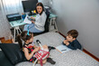 © David Pereiras - Children playing and doing homework talking with their mother who works at home. Conciliation family work concept