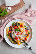 Pasta with eggplant, tomato sauce, basil, served with grated ricotta salata cheese. Pasta alla Norma, pasta salad. Pink and beige table surface. Directly above, vertical image.