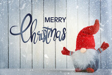 Merry Christmas! Cute Gnome On Table Against White Wooden Background