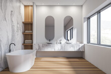 Bright Bathroom Interior With Two Sinks, Bathtub, Oval Mirrors, Window