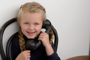 Wall Mural - Girl sitting on chair and talking by old phone