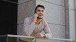 Portrait of cheerful smiling carefree happy hispanic arabic bearded business man boss leader guy standing on balcony terrace talking on mobile phone answering call talking wireless smartphone laughing