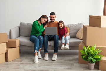 Wall Mural - Arab family using laptop computer in their new apartment