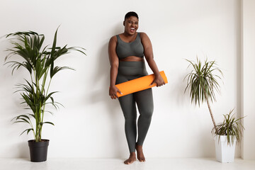 Wall Mural - Pretty african american chubby woman posing with fitness mat