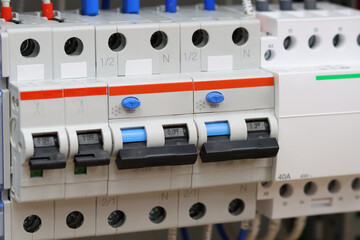 Electric circuit breakers with connected wires are installed in the electrical panel.