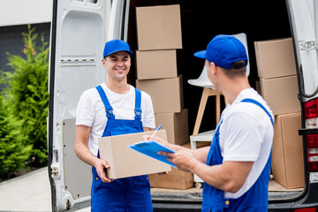 Wall Mural - Two removal company workers unloading boxes from minibus into new home