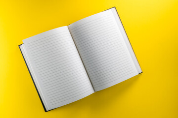 Fototapete - Open lined notebook  isolated on yellow background in top view, flat lay, copy space, clipping path