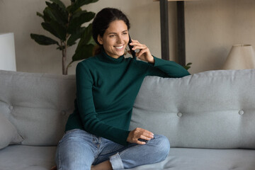 Poster - Smiling young Hispanic woman sit on sofa in living room speak talk on cellphone with good mobile provider connection. Happy Latin female have pleasant smartphone call. Communication concept.