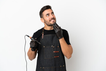 Canvas Print - Tattoo artist man isolated on white background looking up while smiling