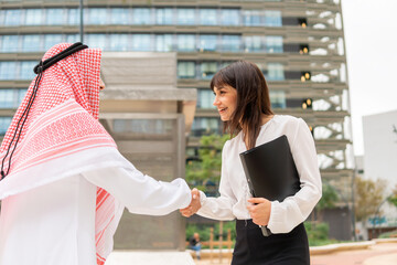 Young pleasant caucasian businesswoman greeting arab male client at meeting outdoors