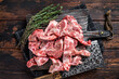 Uncooked Raw meat diced for stew on a butcher board. Dark Wooden background. Top View