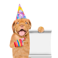 Poster - Happy puppy wearing birthday cap points on empty list. isolated on white background