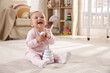 © New Africa - Cute baby girl playing with toy pyramid on floor at home
