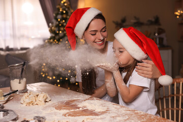 Canvas Print - Mother with her cute little daughter having fun while making dough for Christmas cookies in kitchen