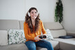 © Westend61 - Happy woman with headphones playing game through joystick at home