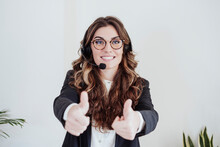 Young sales representative with headset showing thumbs up gesture at office