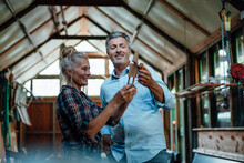 Couple Looking At Wooden Tool In Garden Shed