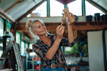 Woman Holding Wooden Tool At Garden Shed