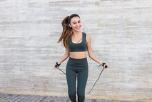 Smiling Athlete With Jump Rope Exercising In Front Of Wall