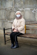 © Vladimir Arndt - Aged woman at bus stop wearing face mask during coronavirus outbreak.