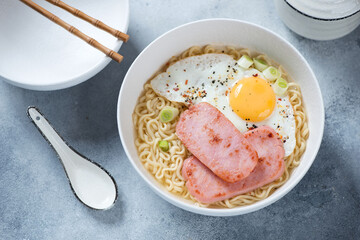 Wall Mural - White bowl with Hong Kong breakfast or Gong Zai Mein, elevated view on a light-blue stone background