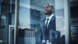 © Gorodenkoff - Thoughtful African-American Businessman in a Perfect Tailored Suit Standing in His Office Looking out of the Window on Big City. Successful Investment Manager Planning Strategy. Outside Shot