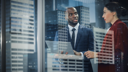 Portrait of Successful Corporate CEO and Investment Manager Talking, Using Laptop Computer while Standing in City Office. Two Successful Businesspeople Brainstorm on e-Commerce Software. Outside Shot