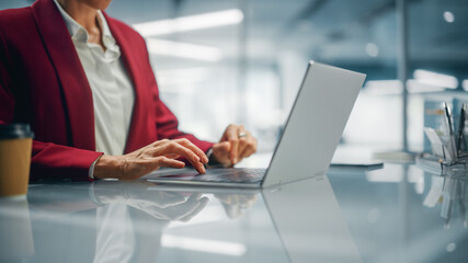 Wall Mural - Stylish Bright Office: Anonymous Businesswoman in Stylish Suit Working on Laptop. Female CEO Working Late on Computer to Achieve Best Results. Colorful Shot Focus on Hands and Computer