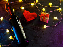 A Bottle Of Wine, A Red Heart And A Gift Box, The Concept Of A Romantic Evening On Valentine's Day. Copy Space Dark Background