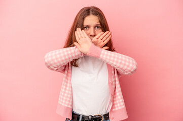 Little caucasian girl isolated on pink background doing a denial gesture