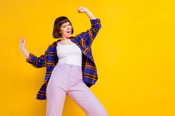 Wall Mural - Portrait of attractive cheerful girl dancing having fun free time clubbing isolated over bright yellow color background