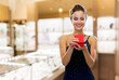 © Syda Productions - christmas, valentine's day and luxury concept - smiling young woman in dress with gift box over jewelry store background
