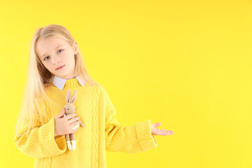 Poster - cute little girl holds toy rabbit on yellow background