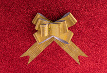 Gold Bow On Red Glittering Background