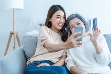 Wall Mural - Asian lovely family, young daughter use phone selfie with older mother