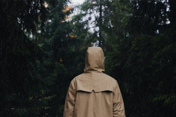 Wall Mural - Woman with raincoat in forest under rain, back view