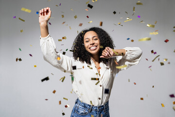 Beautiful young woman at celebration party with confetti falling everywhere on her. Birthday or New Year eve celebrating concept