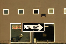 One Way Traffic Sign And Brown Building With Windows