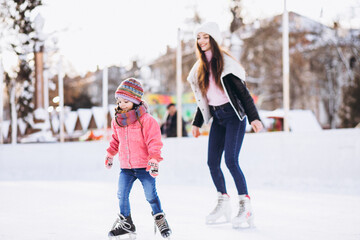 Mother with daughter teaching ice skating on a rink