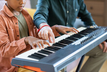 Hand Of Young Teacher Of Music Pointing At One Of Keys Of Piano Keyboard During Lesson In Home Environment