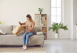 © Studio Romantic - Smiling young woman sit on couch do unpacking at home shopping online. Happy girl client or customer on sofa unbox unpack parcel buy on internet. Good delivery service concept. International shipping.