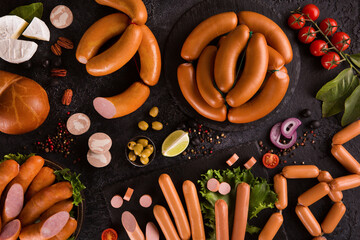 Wall Mural - Sausages and meat delicacies, liver. Cheese, nuts, herbs, tomatoes, onion with spices on a black background. Background image, copy space, flatlay, top view